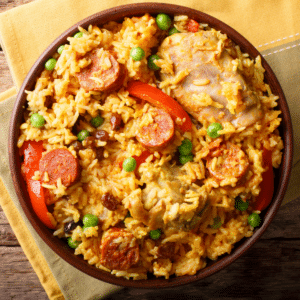 Overhead view of a bowl of Cajun chicken and sausage rice with smoked sausage, chicken, red peppers, and peas.