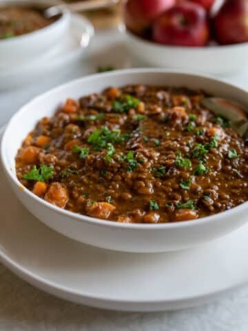 Bowl of thick beef lentil soup with carrots, tender beef, lentils, and parsley.