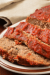 Close-up of sliced meatloaf with a red tomato glaze on a serving plate.