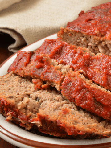 Close-up of sliced meatloaf with a red tomato glaze on a serving plate.