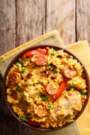A bowl of Cajun chicken and sausage rice with smoked sausage, chicken, red peppers, and peas.
