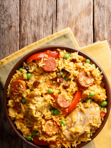 A bowl of Cajun chicken and sausage rice with smoked sausage, chicken, red peppers, and peas.